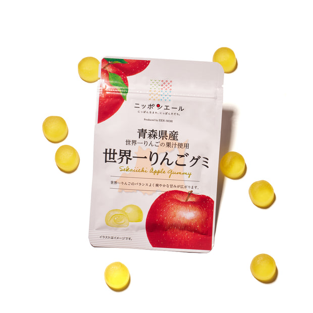 A box of Premium Japanese Fresh Gummy (Orange Box) shows orange fruit on the label and is surrounded by round yellow Japanese gummies on a white background.