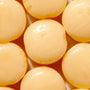 A close up of a bunch of Kasugai Peach Cream Frappe Candy yellow balls. thumbnail 2