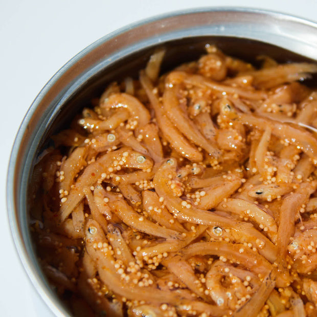 A stainless steel bowl filled with Bokksu Tinned Shirasu Anchovies with Cod Roe, marinated and seasoned for extra flavor.