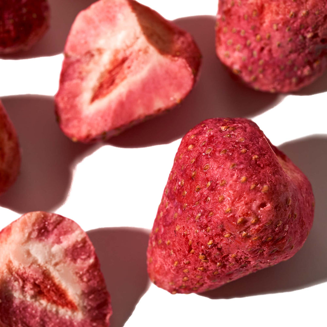 Close-up of freeze-dried White Strawberries, with some whole and others sliced in half, arranged on a white surface with distinct shadows. Perfect for adding to your Bokksu White Strawberry 6-Piece Box (2-Pack) from Bokksu or enjoying as an artisanal Japanese snack.