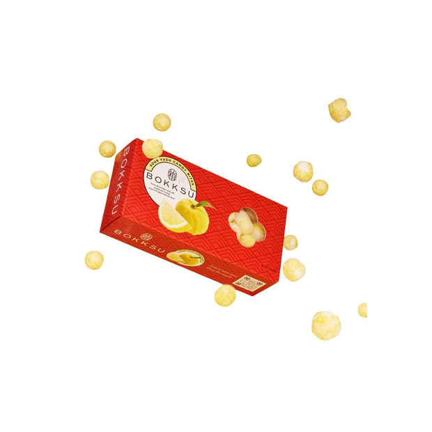 A red Japan Crate Medium Crate with lemon designs sits on a white background, surrounded by small round yellow Japanese snacks featuring yuzu matcha flavors.