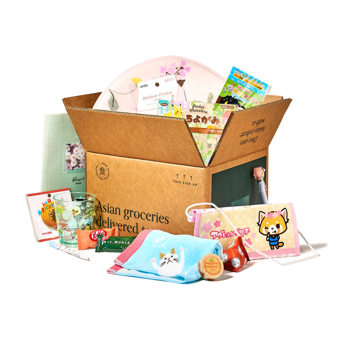 A box labeled "Asian groceries delivered" is open, showcasing a variety of items similar to the Bokksu Holiday Gift Pack, featuring Japan's cutest selections including snacks, books, stickers, and premium stationery items.