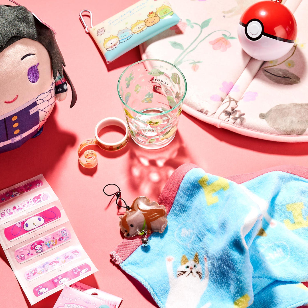 Explore the charming "Holiday Gift Pack" by Bokksu, showcasing Japan's cutest items on a pink surface. This adorable collection includes a character plushie, a Pokémon ball, a glass, stickers, a keychain, a towel, and decorative tape—making it perfect for fans of whimsical charm.