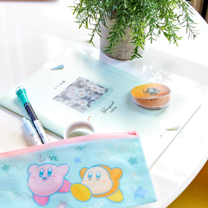 A white table is adorned with the &quot;Kawaii Gift Pack - Stationery Surprises &amp; Japanese Chocolate Treats&quot; by Bokksu, featuring notebooks, pens, pencils, erasers, and a pouch with cartoon characters. A potted plant adds natural charm to the scene. thumbnail 6