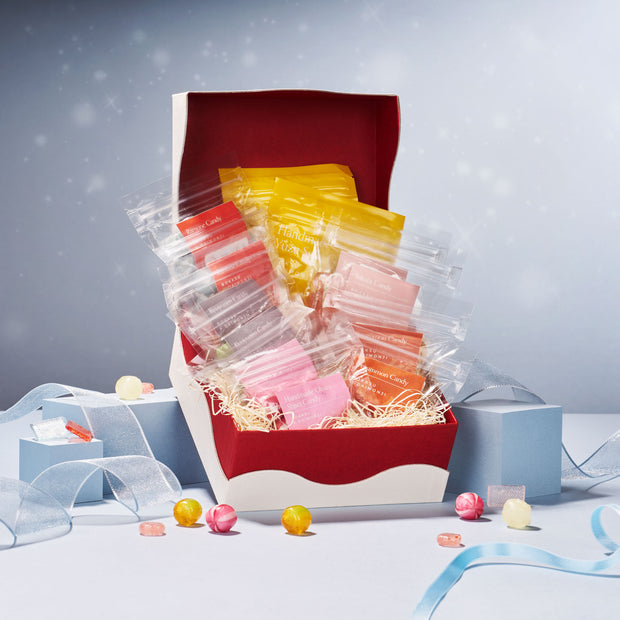 An open Daimonji Ame Honpo Handmade Candy Gift Box (12 Bags, 6 Flavors) displays individually wrapped Kyoto candies, pastel-colored and surrounded by ribbons, small gift boxes, and assorted treats.