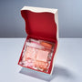 An open Daimonji Ame Honpo Handmade Candy Gift Box (12 Bags, 6 Flavors) with a red interior displays clear bags of pink "Sakura Candy" and orange "Pomegranate Candy," among other Kyoto handmade sweets. thumbnail 2