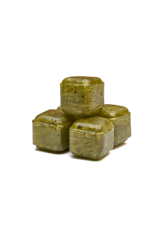 Four greenish-brown Bokksu Sweet Matcha Drops stacked on a white background.