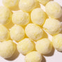 Several round, yellow Sour Yuzu Japanese Candy Bites (0.75oz) are arranged closely together on a white surface under bright lighting, highlighting the enticing citrus flavor of this Japanese treat. thumbnail 3