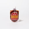 A pouch of Bokksu Fiery Garlic Chili Sauce, a Japanese chili garlic paste, with a white cap and red label featuring yellow accents, stands upright against a plain white background.