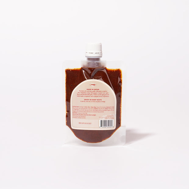 Bokksu Fiery Garlic Chili Sauce (2-Pack) comes in clear plastic pouches with screw caps and white front labels. This reddish-brown chili garlic paste is made in Japan.