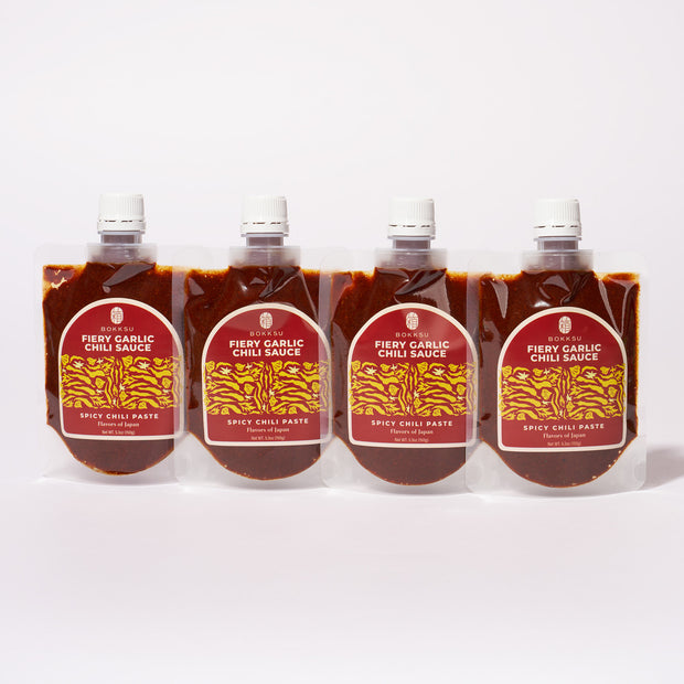 Four pouches of Bokksu Fiery Garlic Chili Sauce (4-Pack), a bold chili garlic paste made in Japan, are arranged side by side with red labels and white caps against a white background.