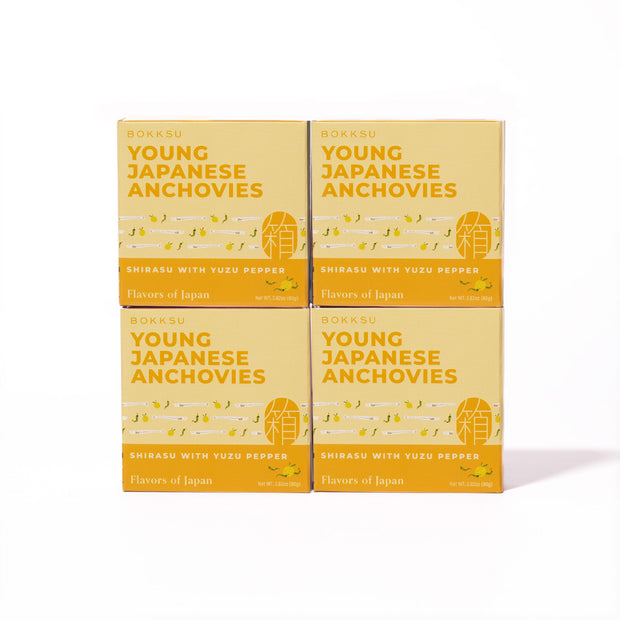 Four boxes of Bokksu Tinned Shirasu Anchovies with Yuzu Pepper (4-Pack) are arranged in a two-by-two grid on a white background—a perfect protein snack infused with the zesty spice of yuzu kosho.