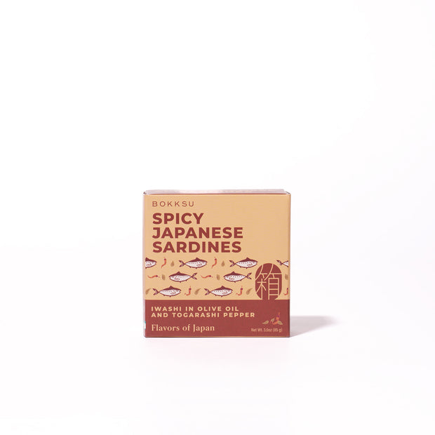 A box of Bokksu Spicy Japanese Sardines is shown on a plain white background, featuring illustrated sardines and text describing iwashi in olive oil with togarashi pepper.