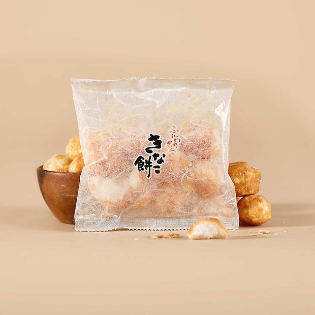 A clear package of Doki Doki Snack Mix: Japan Mochi Puffs with black Japanese text on the front sits in front of a bowl filled with more mochi puffs on a beige background.