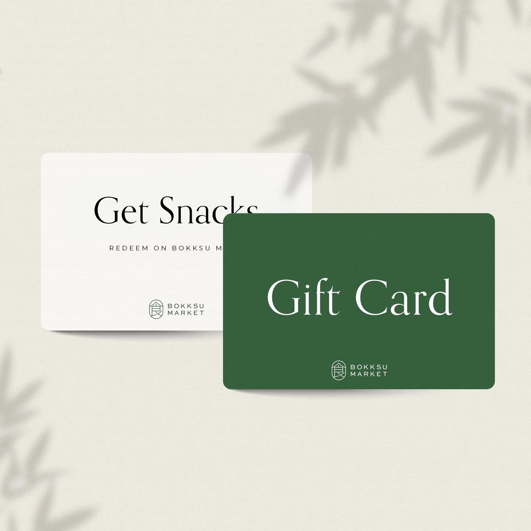 Two Bokksu Market cards: white with "Get Snacks" and green with "Gift Card", on a light backdrop with leaf shadows. Ideal for exploring Asian groceries, the Bokksu Digital Gift Card delivers curated treats to your door.