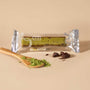 A packaged green cake slice labeled "Cute Selection" sits beside a wooden spoon with green powder and chocolate pieces on a beige surface, evoking the delightful Japanese snacks from the Bokksu Snack Box: Seasons of Japan. thumbnail 5