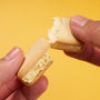 Two hands break apart a sandwich cookie with creamy yellow filling against a yellow background, highlighting April & thumbnail 5