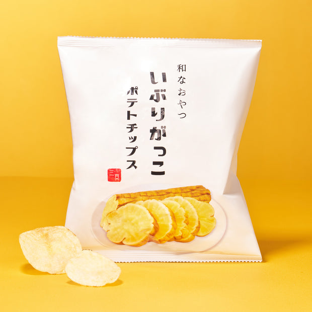 A white bag of Japanese potato chips—featuring chips and smoked daikon on the front—rests on a yellow background with some crisps beside it. A tasty addition to The Japanese Savory Snack Box.