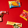 A vibrant selection of Japanese snacks—including a fish-shaped wafer and a variety of colorful packaged treats—arranged on a red background captures the playful spirit of the Dagashi Snack Crate (FBA), a Japanese Snack Variety Box featuring candy, chocolate, cookies, mochi, and Ramune treats. thumbnail 6