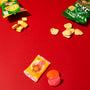 Two opened snack bags with crackers spill onto a red surface. Below, an orange-wrapped Japanese candy sits beside an unwrapped red and pink sweet—just a glimpse of the classic treats you’ll discover inside the Dagashi Snack Crate (FBA), a Japanese Snack Variety Box packed with candy, chocolate, cookies, mochi, and Ramune treats. thumbnail 7