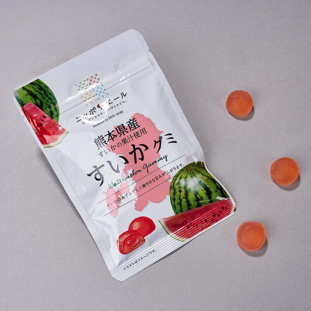 A Japanese Fruits Gummy Box with watermelon images and Japanese text is shown on a gray background, alongside three round watermelon candies.