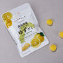 A white package of Japanese Fruits Gummy Box with sliced yuzu fruit images sits beside three yellow gummies on a gray surface—an enticing treat for fans of authentic Japanese flavors. thumbnail 4