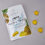 A white pouch labeled "Pineapple Gummy" with Japanese text and a pineapple image sits beside four round yellow gummies on a gray surface, highlighting the authentic flavors found in the Japanese Fruits Gummy Box. thumbnail 5