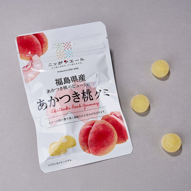 A box of Japanese Fruits Gummy with four round yellow gummies beside the packaging on a gray surface, offering authentic Japanese flavors in every bite.