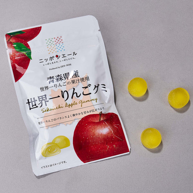 A Japanese Fruits Gummy Box with three yellow gummies beside it on a gray surface, offering authentic Japanese flavors in every bite.
