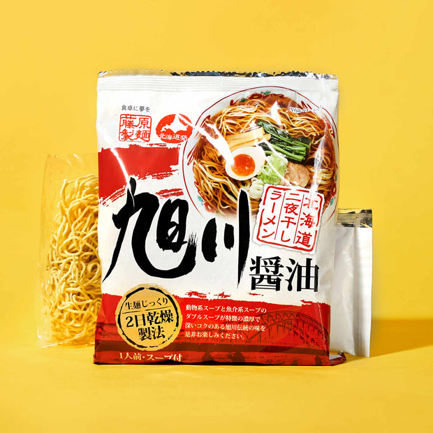 A package of soy sauce-flavored Japanese instant ramen by Bokksu is shown with its soup base packet on a yellow background—ideal for instant soup lovers or as part of The Japanese Savory Snack Box.
