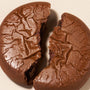 A close-up of a round chocolate cookie broken in half on a light surface, highlighting the rich flavor inspired by Japanese snacks from the Bokksu Snack Box: Seasons of Japan. thumbnail 13