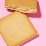 Two square beige cookies, one bitten, sit on a pink surface. These Japanese treats from the Bokksu Snack Box: Seasons of Japan feature a smooth top and creamy filling, delivering authentic Japanese flavor in every bite. thumbnail 14
