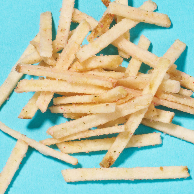 A scattered pile of thin, crispy French fries on a bright blue background, evoking the Japanese treats found in the Bokksu Snack Box: Seasons of Japan.