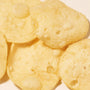 Close-up of crispy, light-yellow Japanese snacks with a bubbled surface, overlapping on a neutral background—experience authentic flavors with the Bokksu Snack Box: Seasons of Japan. thumbnail 9