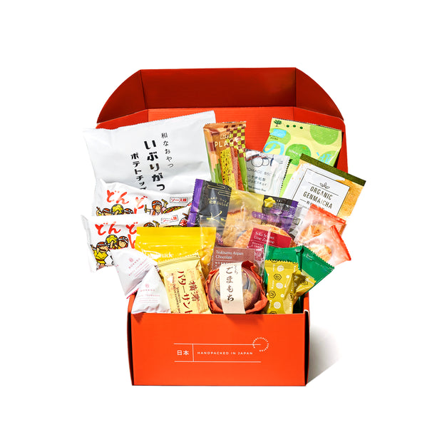 An open Bokksu Snack Box: Seasons of Japan (FBM) displays a vibrant assortment of Japanese snacks in colorful packaging, all neatly arranged upright and slightly overlapping inside the box.