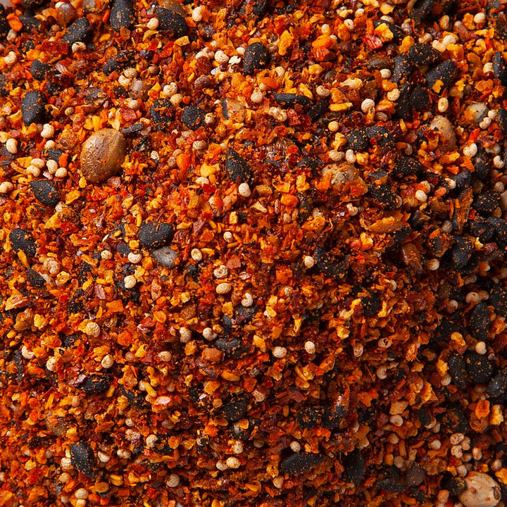 Close-up of S&amp;B Shichimi Togarashi Seven-Spice Pepper, a blend from Japanese cuisine featuring a textured mix of red, orange, and dark brown granules and seeds. thumbnail 2