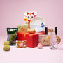 The Cat Lover’s Box showcases a curated assortment of Japanese cat-themed gifts—including snacks, cookies, candies, and adorable ceramics—elegantly displayed on a red box set against a pink background. thumbnail 1