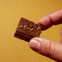 A hand holds a small rectangular chocolate dessert with a crumbly top—one of the treats from April & thumbnail 14